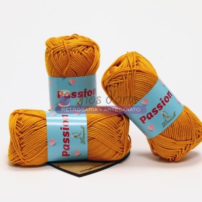 Três novelos de lã amarelo-alaranjado com rótulos azuis com texto Passion