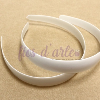 Duas tiaras brancas em plástico sobre superfície bege