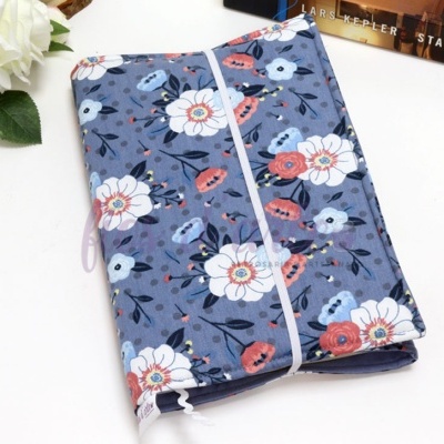 Capa de tecido azul com padrão floral colorido fechada com fita elástica branca