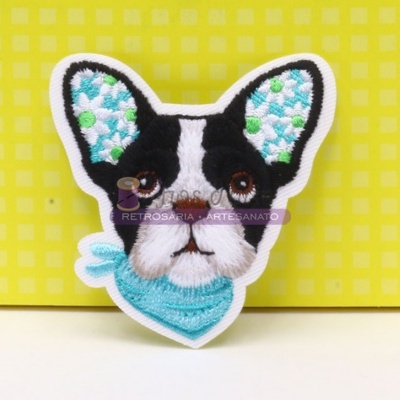 Broche bordado em forma de cabeça de cão com lenço azul sobre fundo amarelo quadriculado