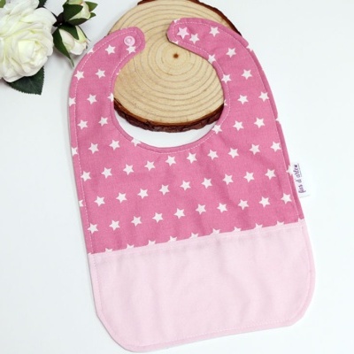 Babete rosa com estrelas brancas sobre base de madeira