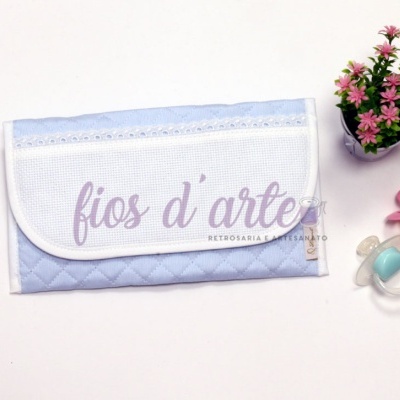 Bolsa azul claro acolchoada com renda, duas chupetas e vaso com flores cor-de-rosa