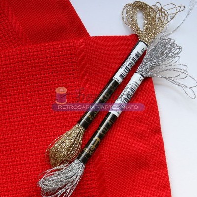 novelos de fio metálico dourado e prateado sobre superfície vermelha e branca