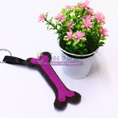 Chaveiro em forma de osso rosa e castanho junto a vaso branco com flor artificial rosa