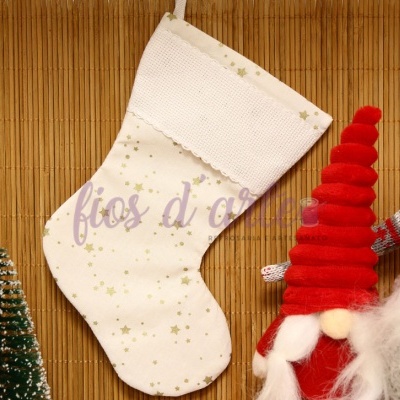 Meia de Natal branca com estrelas douradas pendurada ao lado de figuras de duendes vermelhos e uma pequena árvore de Natal