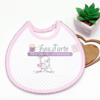 Babete branco e rosa com desenho de urso, planta artificial e forma de coração em madeira