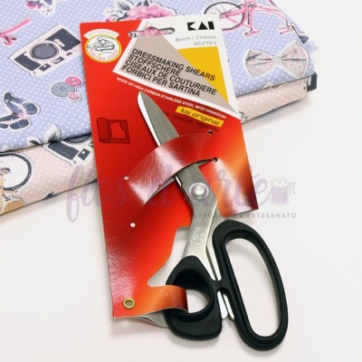 Tesoura para costura com cabo preto e lâminas de aço inoxidável sobre tecidos coloridos