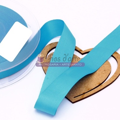 Fita azul clara em tecido enrolada numa bobina plástica com um coração de madeira clara ao fundo