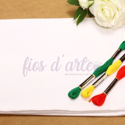 Toalha branca com novelos de linha colorida e rosa branca sobre fundo castanho