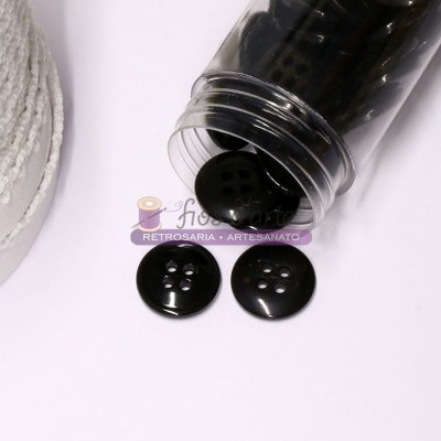 Botões pretos de plástico com quatro furos fora de frasco transparente, carretel de corda branca ao lado.