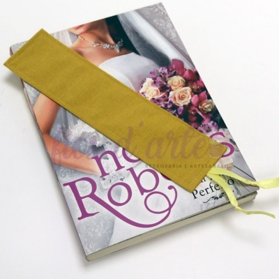 Marcador de livros amarelo esverdeado com fita sobre livro com noiva e flores