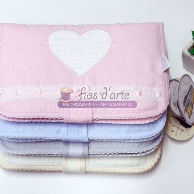 Capas de almofadas em várias cores pastel com bordados em forma de coração e detalhes rendados.