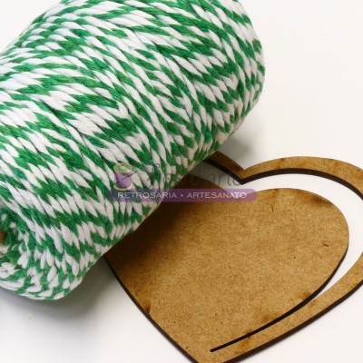Rolo de fio verde e branco e forma de coração em madeira sobre superfície clara