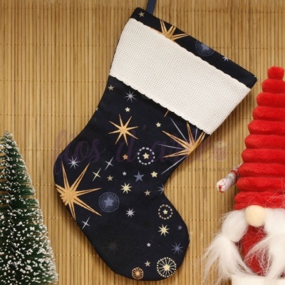 Meia de Natal preta com estrelas e topo branco, ao lado de árvore de Natal e gnomos decorativos