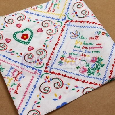 Pano de tecido branco com estampado colorido e texto bordado.
