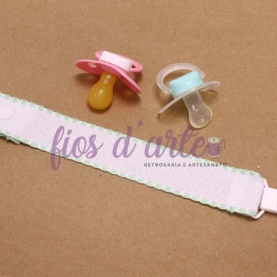 Chupetas rosa e azul com fita para chupeta rosa clara sobre superfície castanha