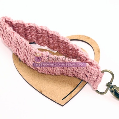 Pulseira trançada rosa com fecho metálico sobre cartão em forma de coração