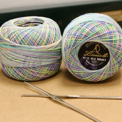 Novelos de fio multicolorido com etiqueta e duas agulhas de crochê