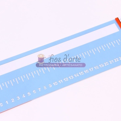 Régua branca com escala em centímetros sobre fundo azul claro com embalagem