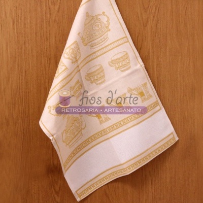 Pano de cozinha branco com estampas douradas de sushi pendurado numa porta de madeira