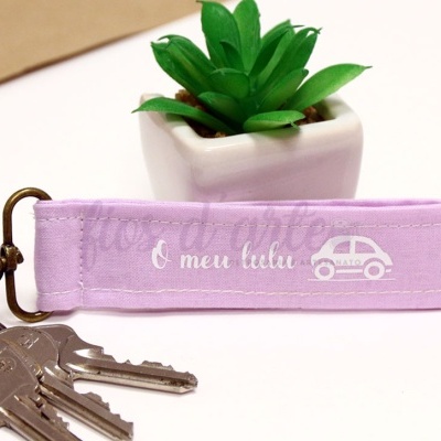 Anilha porta-chaves roxa com texto e ícone de carro, três chaves e vaso com planta