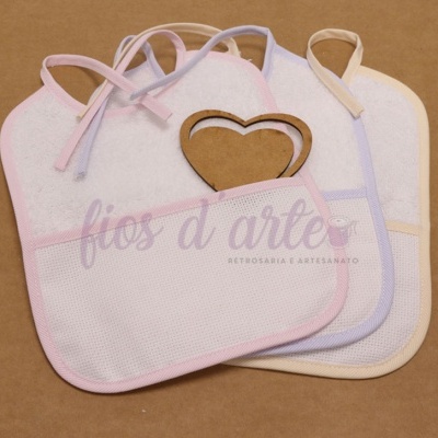 Três babetes de bebé brancos com bordas coloridas e um coração de madeira