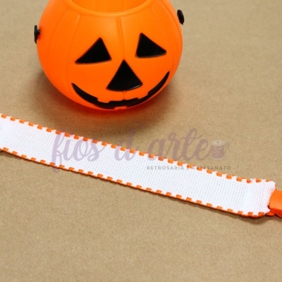 Pulseira branca com bordas laranja e clipe plástico ao lado de lanterna de abóbora de Halloween