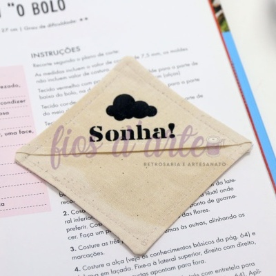 Pega de tecido bege claro com nuvem preta e texto 'Sonha!'