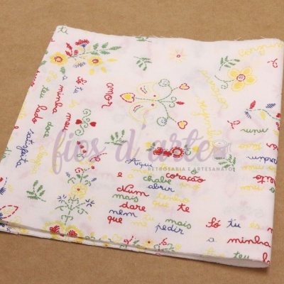 Toalha branca com bordados coloridos de flores, corações e texto em várias cores