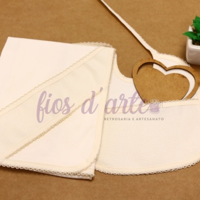 Conjunto manta e babete branco com renda e planta em vaso branco