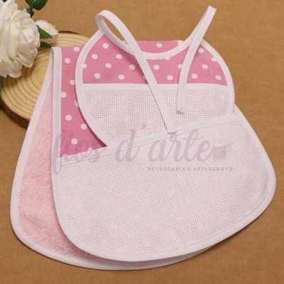 Babete rosa com bolinhas brancas e babete rosa claro com parte frontal em malha e fita para amarrar, ambos sobre superfície castanha