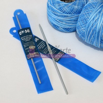 Cones de linha azul clara e agulhas de metal com embalagens azuis sobre fundo branco