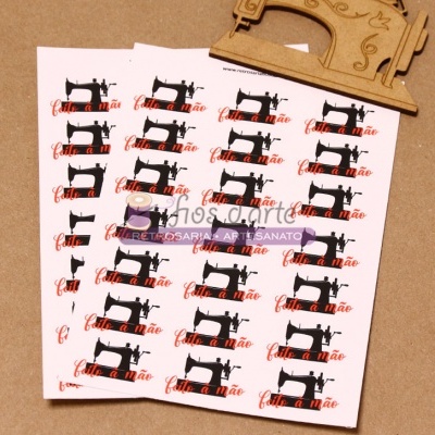 Cartões com desenho de máquina de costura e texto 'feito à mão' sobre superfície castanha