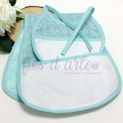 Babetes de bebé azuis com diferentes texturas e padrão infantil, junto a uma flor branca.