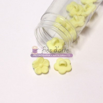 Frasco com botões amarelos em forma de flor sobre superfície branca