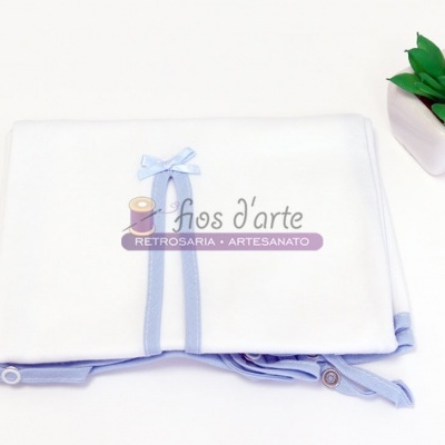 Fralda branca com borda azul e laço, ao lado de planta suculenta num vaso branco