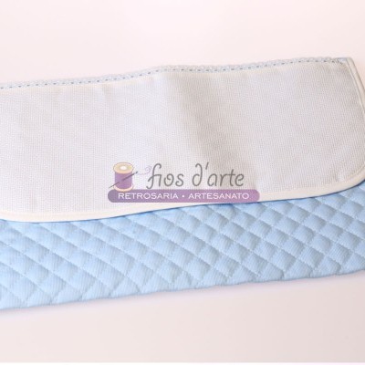 Tecido acolchoado azul claro com tecido branco liso e etiqueta com texto sobre superfície branca