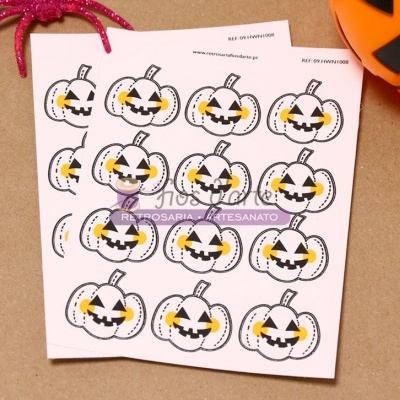 Folha com imagens de abóboras de Halloween em papel sobre superfície castanha com decoração ao redor