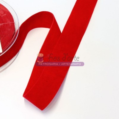 Fita de veludo vermelha em rolo plástico com etiqueta numa superfície branca