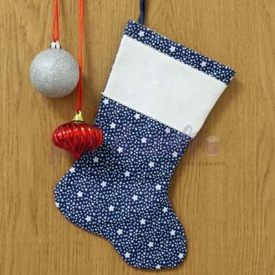 Meia de Natal azul com estrelas brancas e punho branco, pendurada na parede de madeira ao lado de ornamentos natalícios prateado e vermelho.