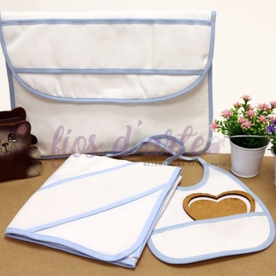 Conjunto branco com detalhes azuis para bebé, com babete, toalha e saco organizador, com vasos de flores decorativos ao lado