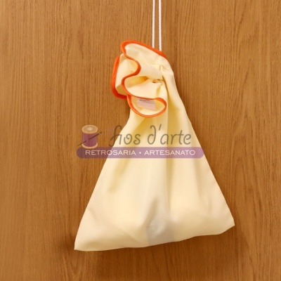 Saco de tecido amarelo pálido com acabamento laranja pendurado em cordão branco