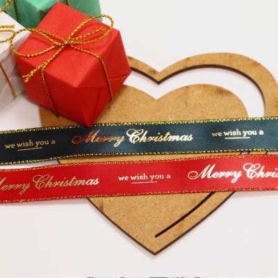 Presentes pequenos embrulhados com fitas e fitas decorativas com texto de Natal sobre coração de madeira