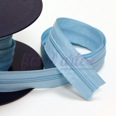 Fecho éclair azul claro enrolado numa bobina preta sobre fundo branco