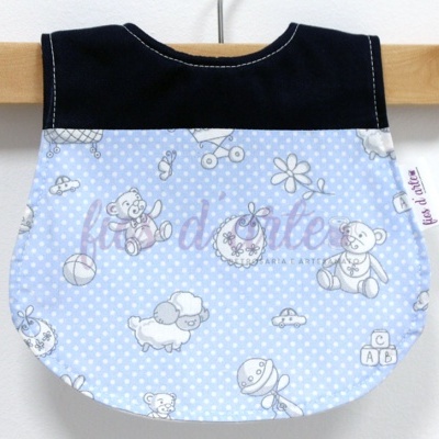 Babete azul claro com padrão de bolinhas brancas e ilustrações de ursinhos e brinquedos, parte superior preta