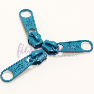 Três pegas de fecho éclair azuis turquesa com texto 'Love' em relevo num fundo branco