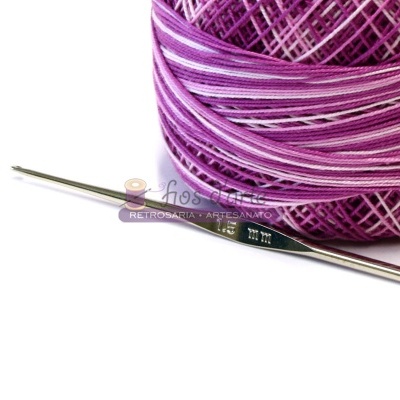 Rolo de fio roxo e branco com agulha de crochet