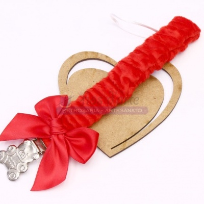 Chupeta felpuda vermelha com laço e ursinho prateado sobre coração de madeira