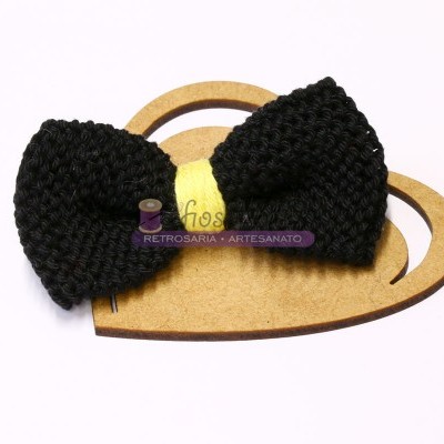 Laço preto tricotado em cartão de coração castanho claro com etiqueta amarela.