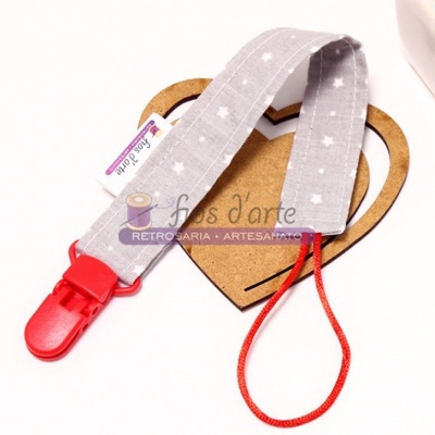 Clipe para chupeta com fita cinza e clip vermelho sobre cartão com coração